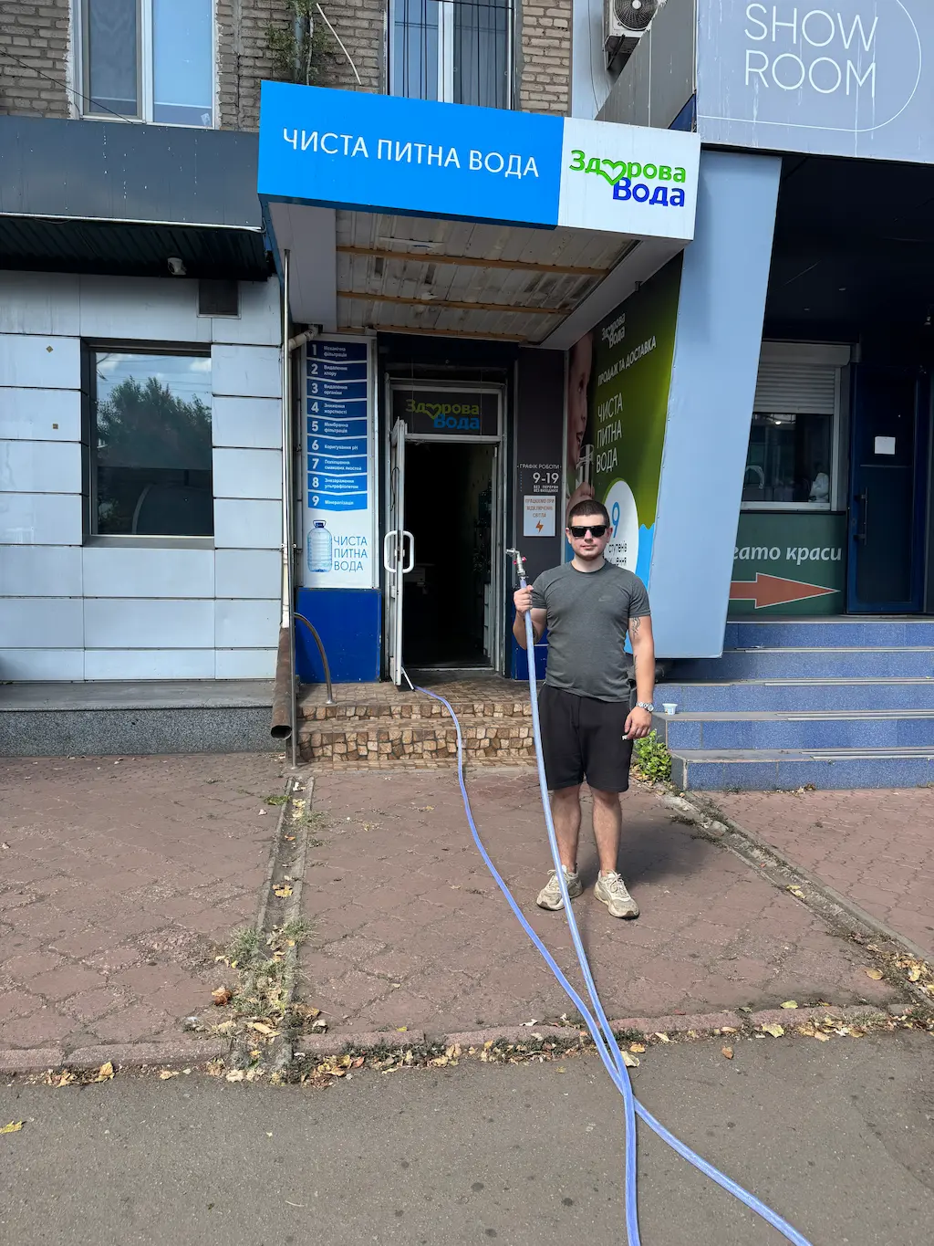 Процес заправки автоцистерни питною водою біля магазину